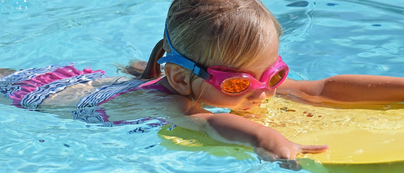 Kind mit Schwimmbrett im Wasser