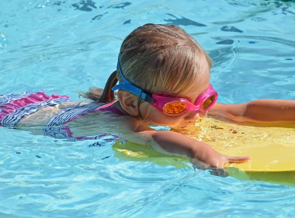 Kind mit Schwimmbrett im Wasser