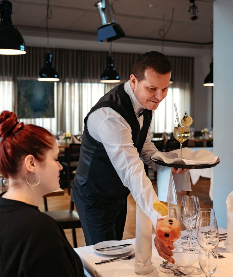 Servicemitarbeiter bedient Gäste im Restaurant